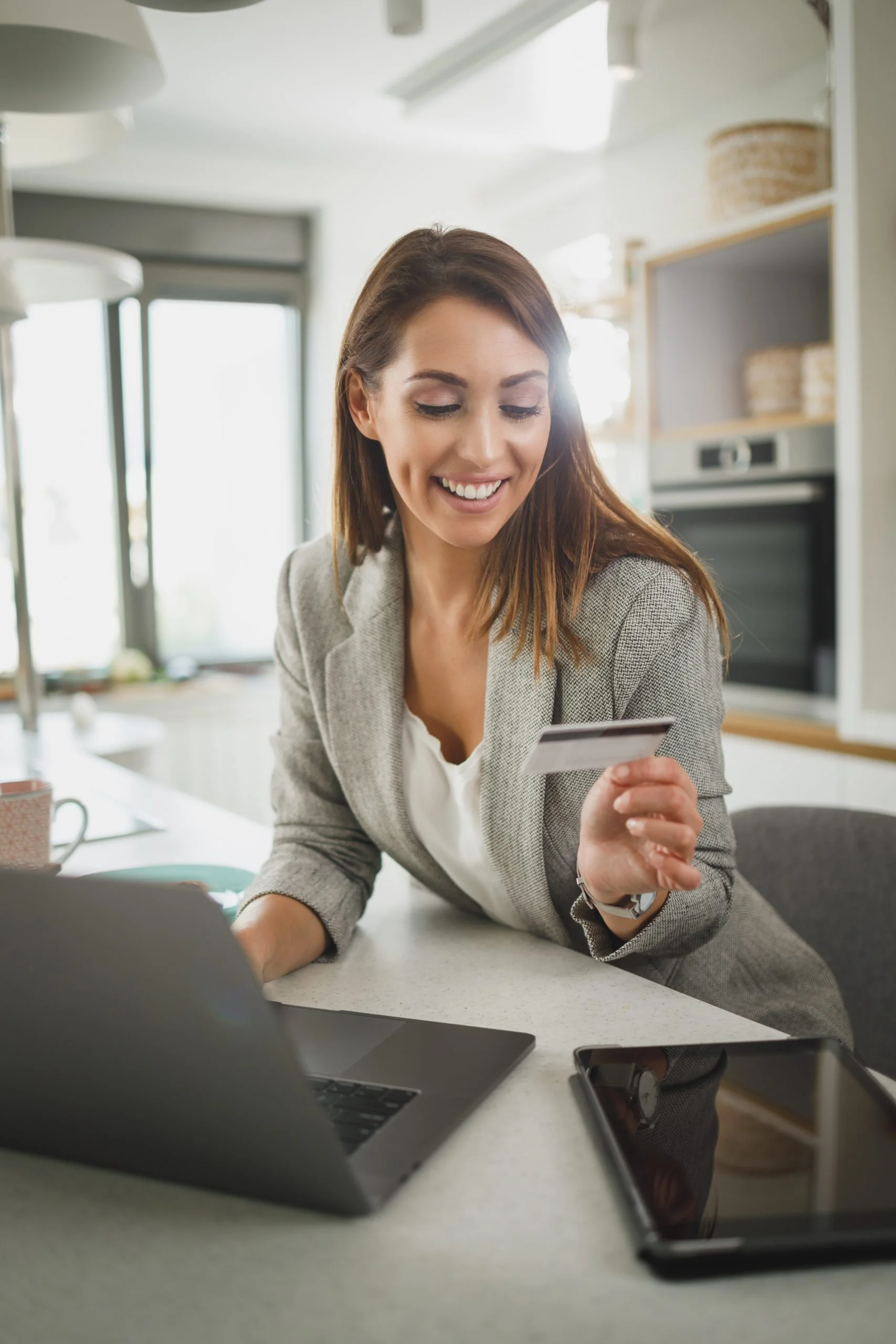 Shot of a young business woman using on her laptop while shopping online in the her kitchen while getting ready to go to work.