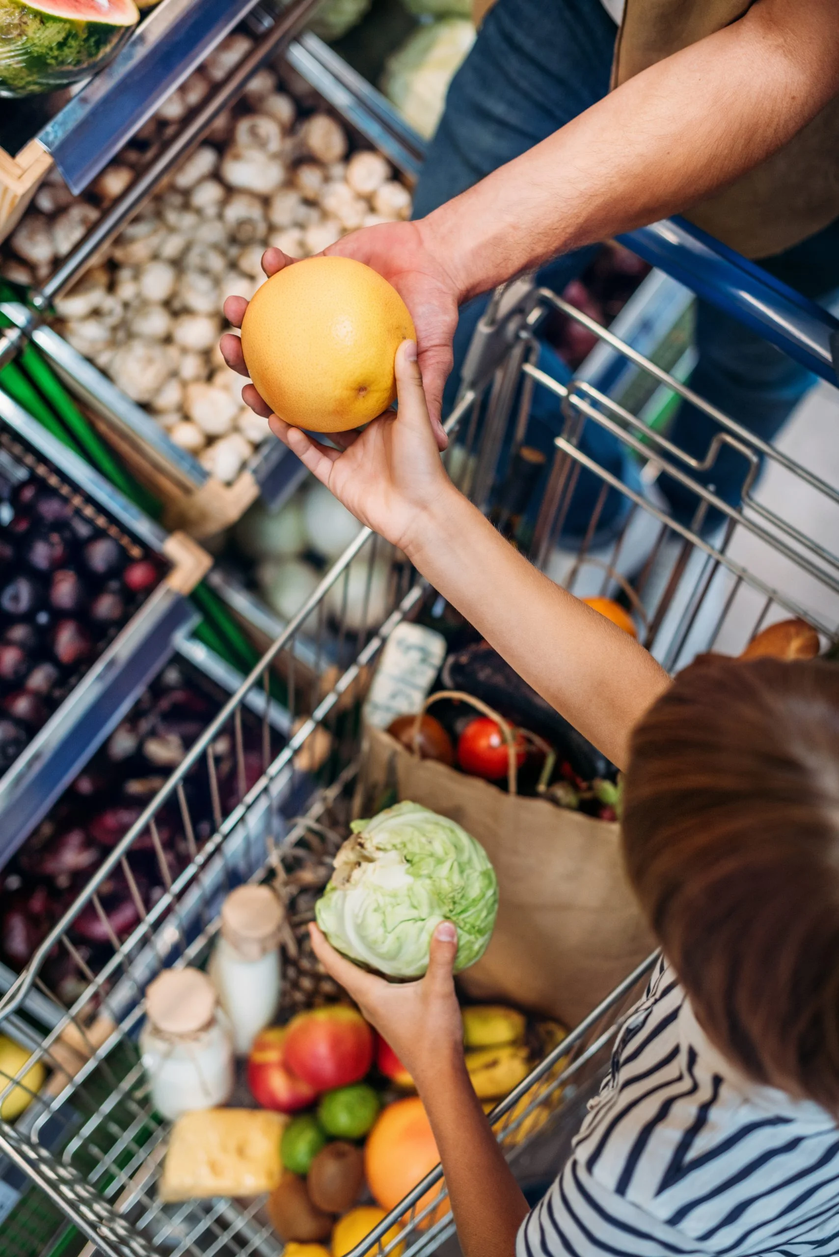 overhead view of little child helping parent during shopping in grocery shop